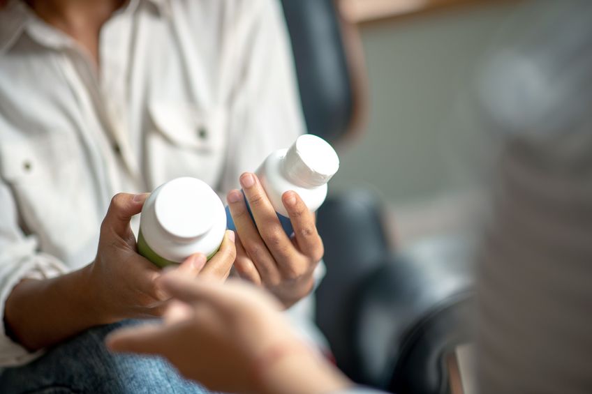 Woman looking at two different labels of health supplements